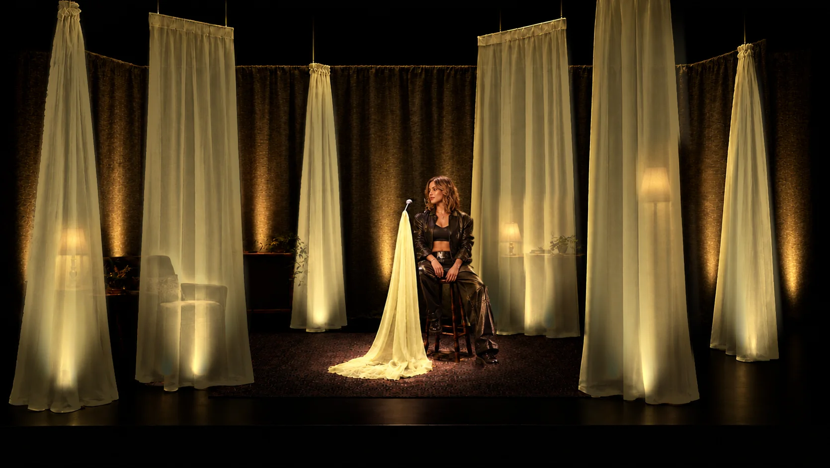 V1 show look: six irregular Apple voile pieces, rear-lit, with a fictional stand-in seated at the mic